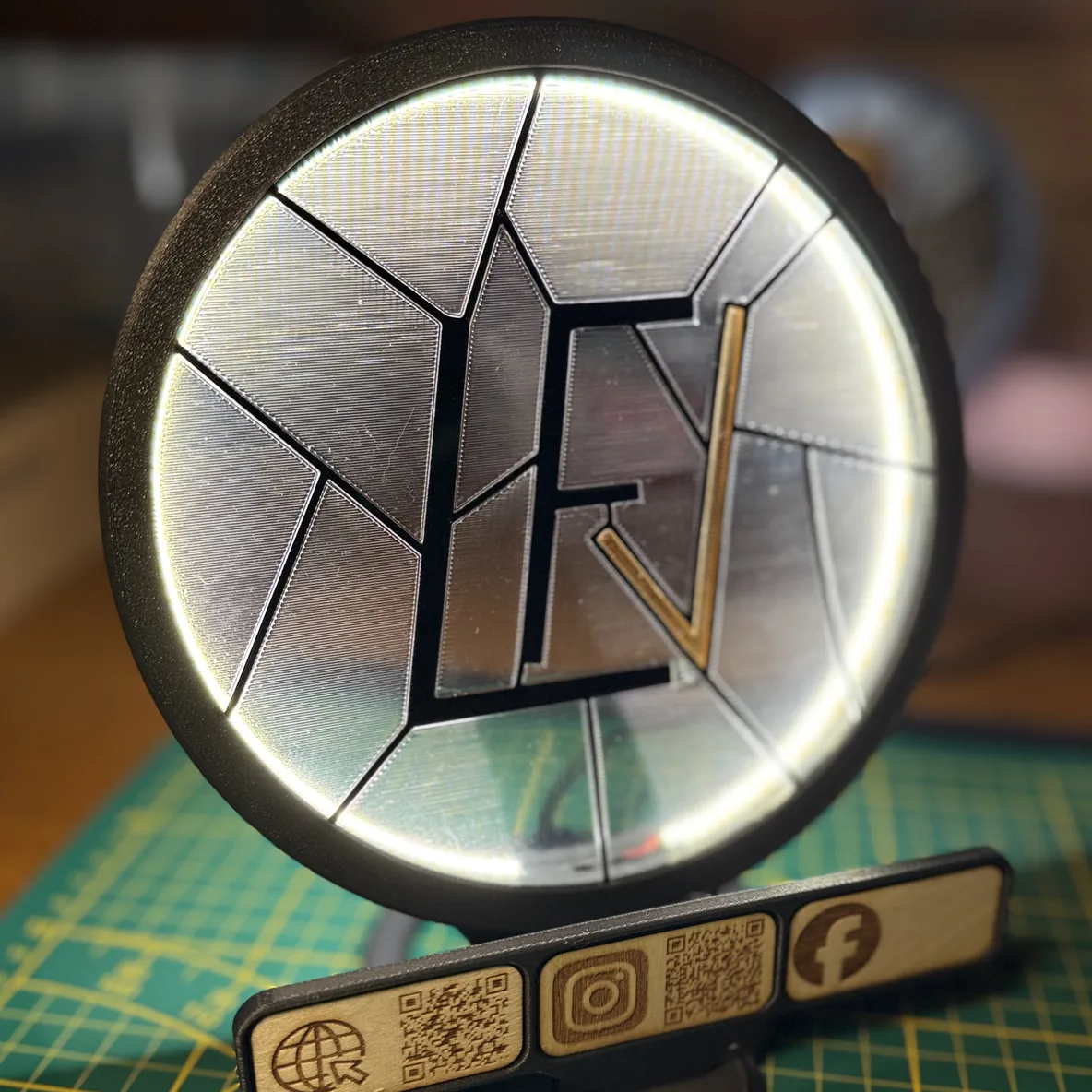 Le Socle Vitrail LED allumé, avec une plaque gravée portant les icônes site web, Instagram et Facebook accompagnées de QR codes, clipsée en dessous.