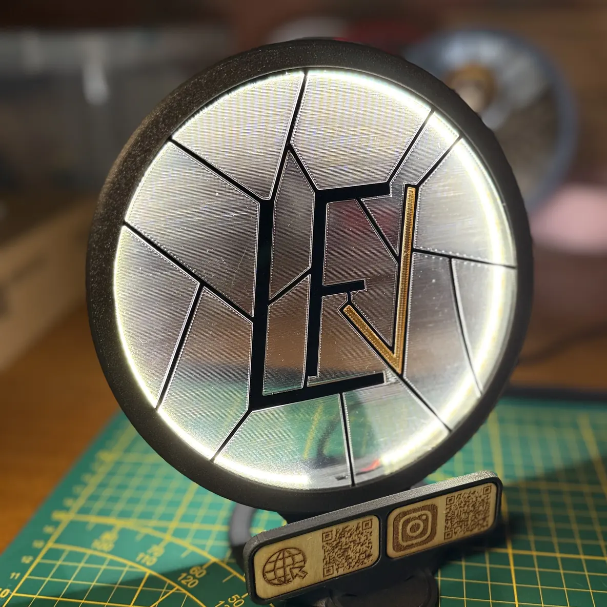 Le Socle Vitrail LED allumé, avec une plaque gravée portant les icônes site web et Instagram accompagnées de QR codes, clipsée en dessous.