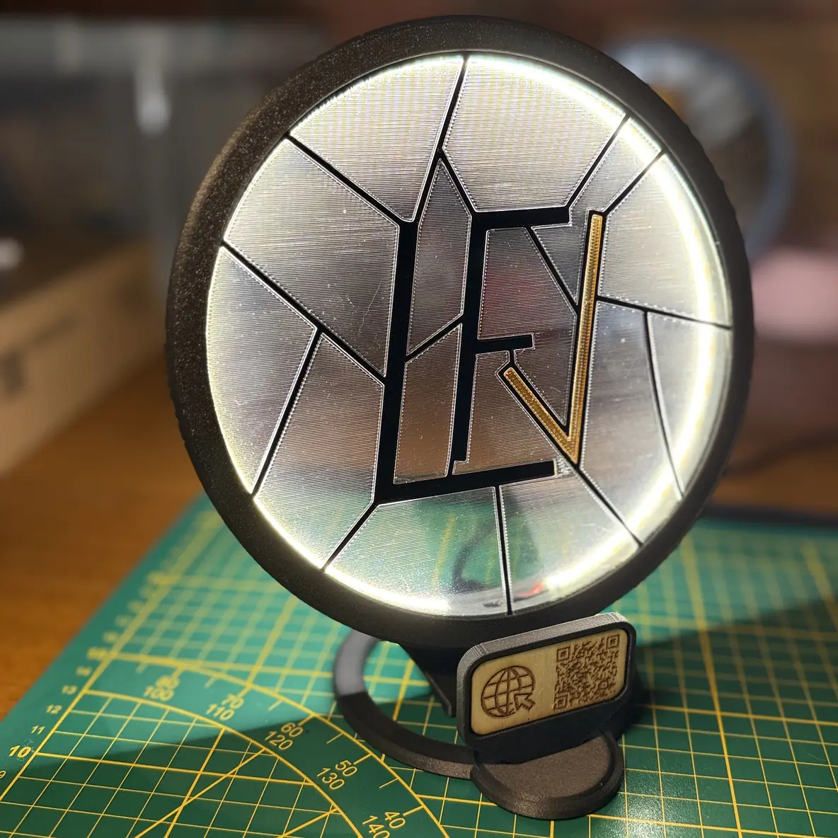 Le Socle Vitrail LED allumé, avec une petite plaque gravée portant l'icône site web et un QR code, clipsée en dessous.